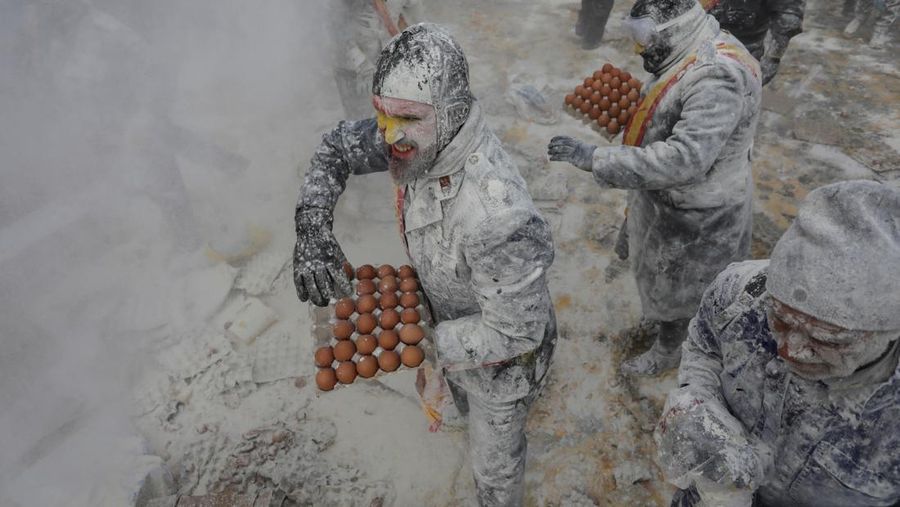 Orang-orang yang bersuka ria berebut tepung dan telur selama festival tradisional 