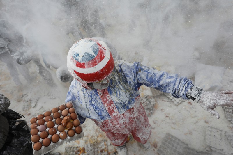 Orang-orang yang bersuka ria berebut tepung dan telur selama festival tradisional Orang-orang yang bersuka ria berebut tepung dan telur selama festival tradisional