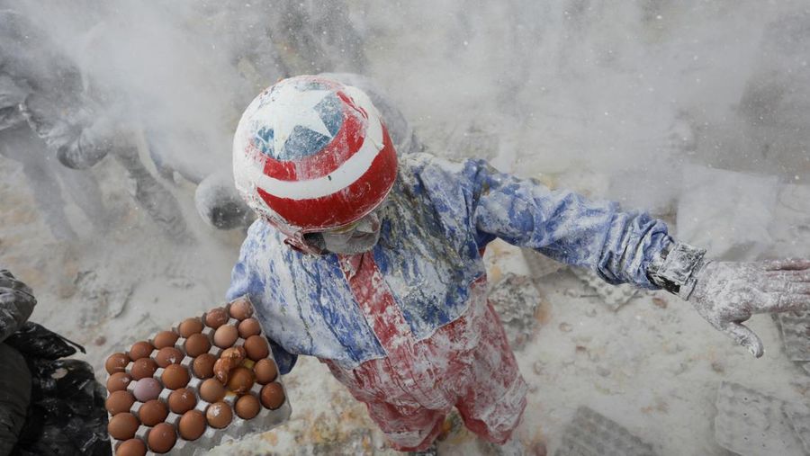 Orang-orang yang bersuka ria berebut tepung dan telur selama festival tradisional 