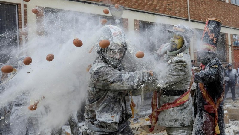Orang-orang yang bersuka ria berebut tepung dan telur selama festival tradisional 