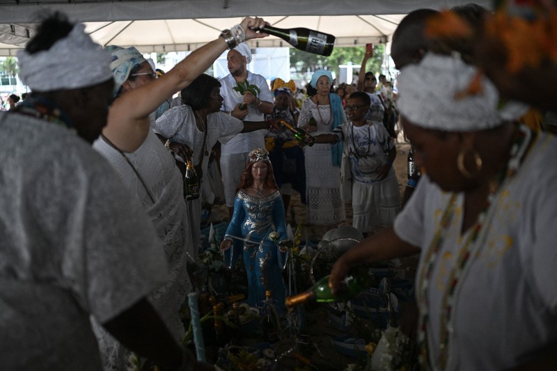 Seorang penganut agama Afro-Brasil memberikan penghormatan kepada Yemanja, dewi laut, dalam perayaan tradisional Malam Tahun Baru di Pantai Copacabana di Rio de Janeiro, Brasil, 29 Desember 2023. (REUTERS/Pilar Olivares)