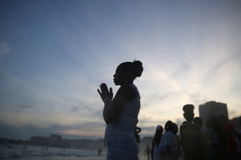 Seorang penganut agama Afro-Brasil memberikan penghormatan kepada Yemanja, dewi laut, dalam perayaan tradisional Malam Tahun Baru di Pantai Copacabana di Rio de Janeiro, Brasil, 29 Desember 2023. (REUTERS/Pilar Olivares)