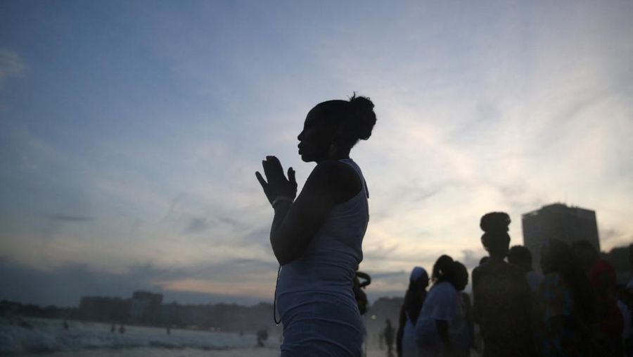 Seorang penganut agama Afro-Brasil memberikan penghormatan kepada Yemanja, dewi laut, dalam perayaan tradisional Malam Tahun Baru di Pantai Copacabana di Rio de Janeiro, Brasil, 29 Desember 2023. (REUTERS/Pilar Olivares)