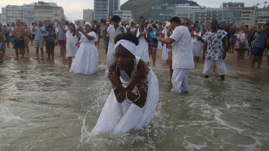 Seorang penganut agama Afro-Brasil memberikan penghormatan kepada Yemanja, dewi laut, dalam perayaan tradisional Malam Tahun Baru di Pantai Copacabana di Rio de Janeiro, Brasil, 29 Desember 2023. (REUTERS/Pilar Olivares)