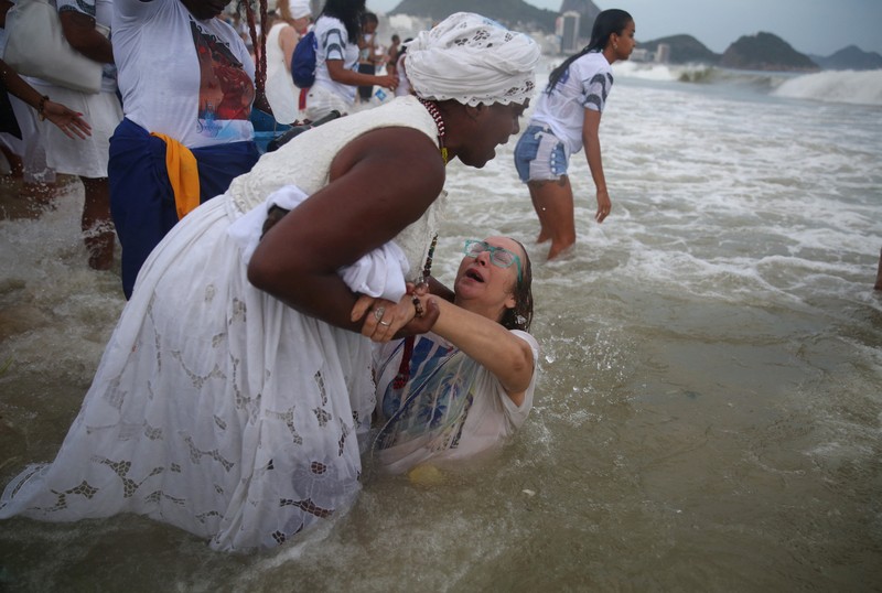 Seorang penganut agama Afro-Brasil memberikan penghormatan kepada Yemanja, dewi laut, dalam perayaan tradisional Malam Tahun Baru di Pantai Copacabana di Rio de Janeiro, Brasil, 29 Desember 2023. (REUTERS/Pilar Olivares)