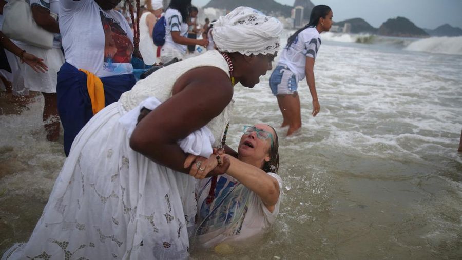 Seorang penganut agama Afro-Brasil memberikan penghormatan kepada Yemanja, dewi laut, dalam perayaan tradisional Malam Tahun Baru di Pantai Copacabana di Rio de Janeiro, Brasil, 29 Desember 2023. (REUTERS/Pilar Olivares)