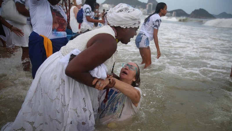 Seorang penganut agama Afro-Brasil memberikan penghormatan kepada Yemanja, dewi laut, dalam perayaan tradisional Malam Tahun Baru di Pantai Copacabana di Rio de Janeiro, Brasil, 29 Desember 2023. (REUTERS/Pilar Olivares)