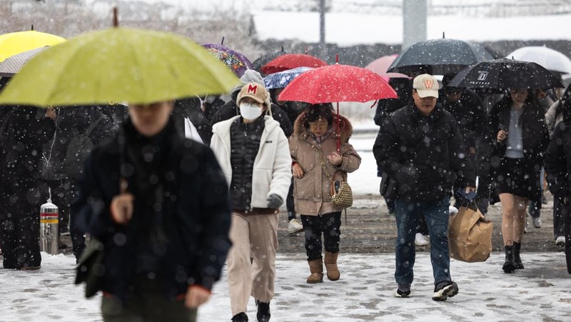 Visitors wearing traditional hanbok dress walk in the snow at Gyeongbokgung palace in central Seoul on December 30, 2023. (JUNG YEON-JE/AFP via Getty Images)