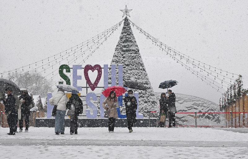 Visitors wearing traditional hanbok dress walk in the snow at Gyeongbokgung palace in central Seoul on December 30, 2023. (JUNG YEON-JE/AFP via Getty Images)