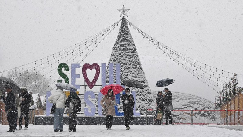 Visitors wearing traditional hanbok dress walk in the snow at Gyeongbokgung palace in central Seoul on December 30, 2023. (JUNG YEON-JE/AFP via Getty Images)