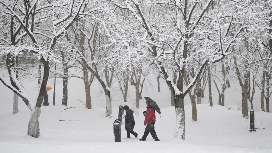 Visitors wearing traditional hanbok dress walk in the snow at Gyeongbokgung palace in central Seoul on December 30, 2023. (JUNG YEON-JE/AFP via Getty Images)