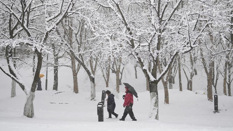 Visitors wearing traditional hanbok dress walk in the snow at Gyeongbokgung palace in central Seoul on December 30, 2023. (JUNG YEON-JE/AFP via Getty Images)
