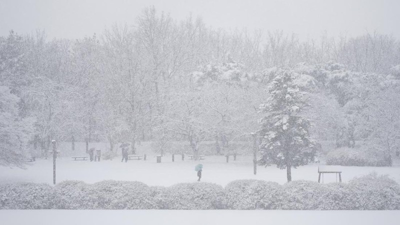 Visitors wearing traditional hanbok dress walk in the snow at Gyeongbokgung palace in central Seoul on December 30, 2023. (JUNG YEON-JE/AFP via Getty Images)