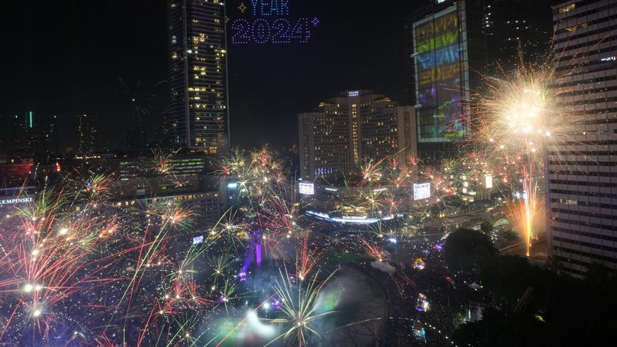 Kembang api meledak saat ribuan orang berkumpul untuk menghadiri perayaan tahun baru di kawasan Bundaran Hotel Indonesia pada Malam Tahun Baru di Jakarta, Indonesia, Senin, 1 Januari 2024. (AP Photo/Achmad Ibrahim)