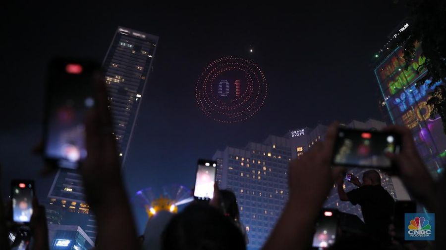 Warga menyaksikan atraksi drone saat Car Free Night (CFN) perayaan malam Tahun Baru 2024 di kawasan Bundaran Hotel Indonesia (HI), Jakarta, Minggu (31/12/2023). (CNBC Indonesia/Faisal Rahman)