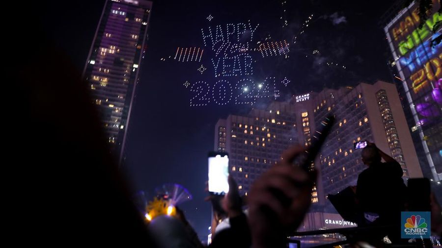 Warga menyaksikan atraksi drone saat Car Free Night (CFN) perayaan malam Tahun Baru 2024 di kawasan Bundaran Hotel Indonesia (HI), Jakarta, Minggu (31/12/2023). (CNBC Indonesia/Faisal Rahman)