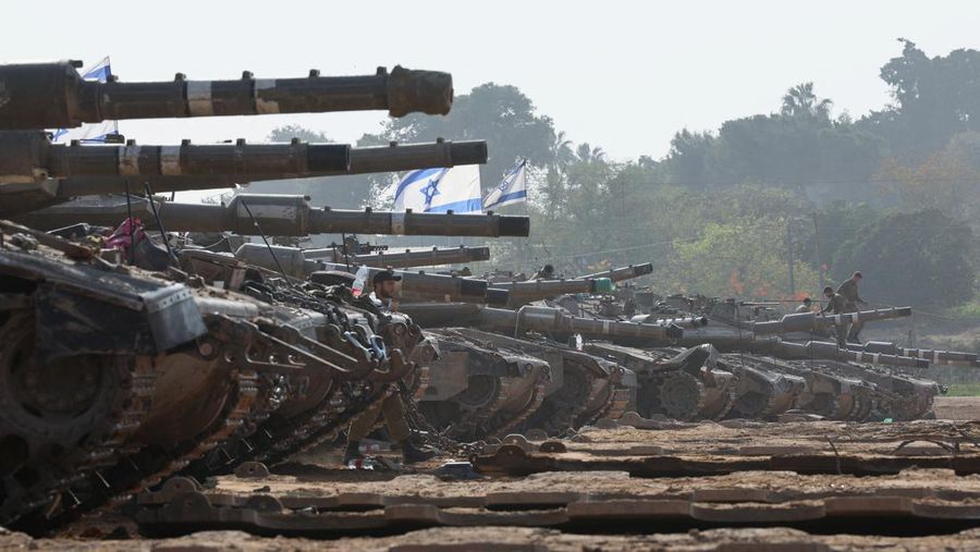 An Israeli soldier walks by tanks, amid the ongoing conflict between Israel and the Palestinian Islamist group Hamas, near the Israel-Gaza border, in southern Israel, January 1, 2024. REUTERS/Violeta Santos Moura