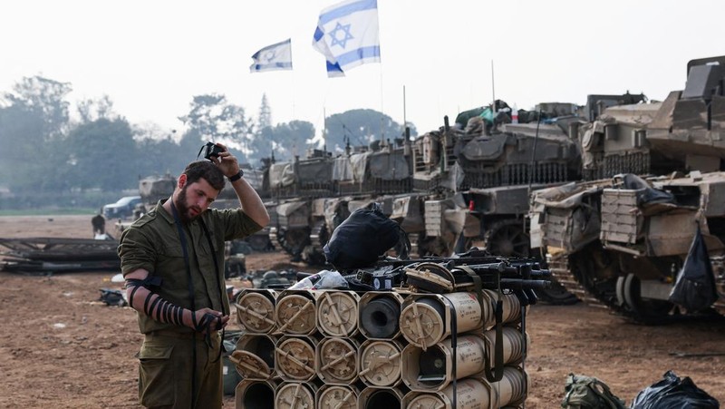 An Israeli soldier walks by tanks, amid the ongoing conflict between Israel and the Palestinian Islamist group Hamas, near the Israel-Gaza border, in southern Israel, January 1, 2024. REUTERS/Violeta Santos Moura
