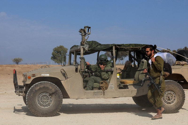 An Israeli soldier walks by tanks, amid the ongoing conflict between Israel and the Palestinian Islamist group Hamas, near the Israel-Gaza border, in southern Israel, January 1, 2024. REUTERS/Violeta Santos Moura