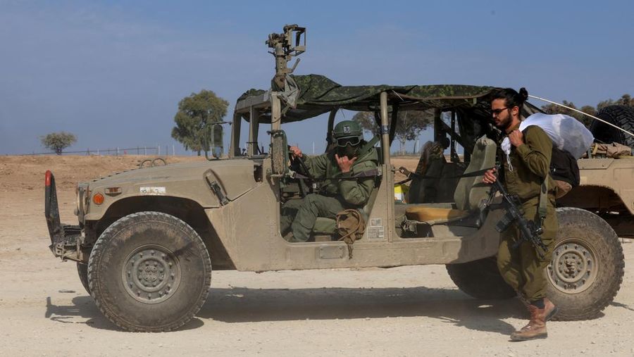 An Israeli soldier walks by tanks, amid the ongoing conflict between Israel and the Palestinian Islamist group Hamas, near the Israel-Gaza border, in southern Israel, January 1, 2024. REUTERS/Violeta Santos Moura