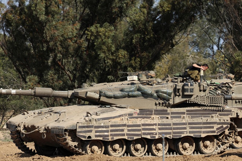 An Israeli soldier walks by tanks, amid the ongoing conflict between Israel and the Palestinian Islamist group Hamas, near the Israel-Gaza border, in southern Israel, January 1, 2024. REUTERS/Violeta Santos Moura