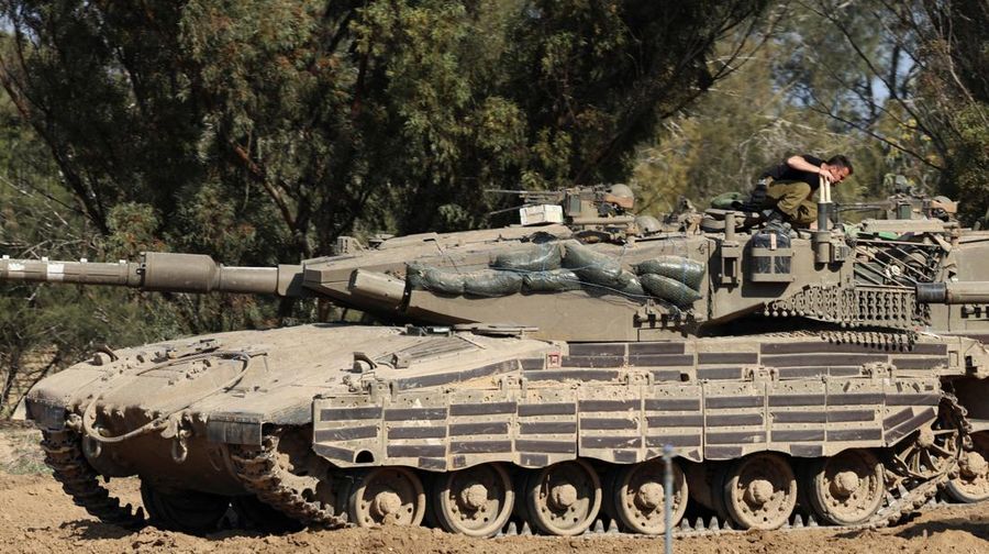 An Israeli soldier walks by tanks, amid the ongoing conflict between Israel and the Palestinian Islamist group Hamas, near the Israel-Gaza border, in southern Israel, January 1, 2024. REUTERS/Violeta Santos Moura