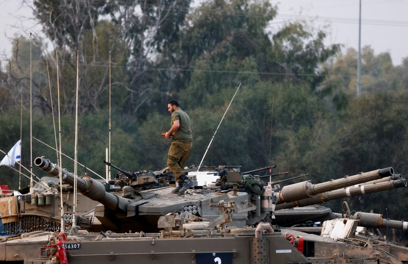 An Israeli soldier walks by tanks, amid the ongoing conflict between Israel and the Palestinian Islamist group Hamas, near the Israel-Gaza border, in southern Israel, January 1, 2024. REUTERS/Violeta Santos Moura