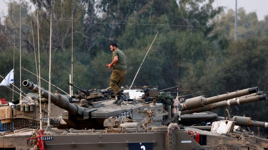 An Israeli soldier walks by tanks, amid the ongoing conflict between Israel and the Palestinian Islamist group Hamas, near the Israel-Gaza border, in southern Israel, January 1, 2024. REUTERS/Violeta Santos Moura
