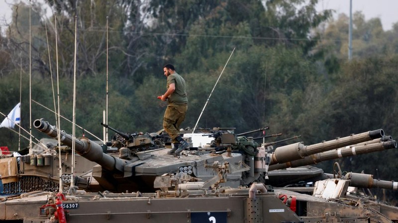 An Israeli soldier walks by tanks, amid the ongoing conflict between Israel and the Palestinian Islamist group Hamas, near the Israel-Gaza border, in southern Israel, January 1, 2024. REUTERS/Violeta Santos Moura