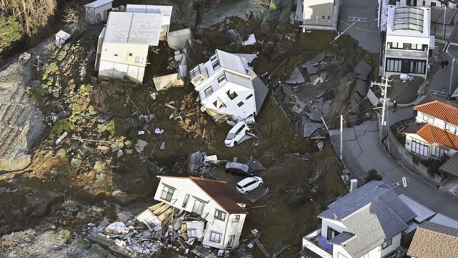 A building falls on the ground following an earthquake in Wajima, Ishikawa prefecture, Japan Tuesday, Jan. 2, 2024. A series of powerful earthquakes in western Japan damaged homes, cars and boats, with officials warning people on Tuesday to stay away from their homes in some areas because of a continuing risk of major quakes and tsunamis. (Kyodo News via AP)