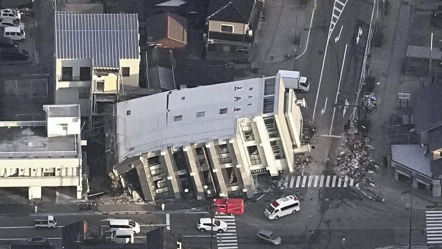 A building falls on the ground following an earthquake in Wajima, Ishikawa prefecture, Japan Tuesday, Jan. 2, 2024. A series of powerful earthquakes in western Japan damaged homes, cars and boats, with officials warning people on Tuesday to stay away from their homes in some areas because of a continuing risk of major quakes and tsunamis. (Kyodo News via AP)