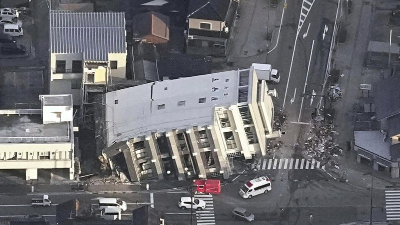 A building falls on the ground following an earthquake in Wajima, Ishikawa prefecture, Japan Tuesday, Jan. 2, 2024. A series of powerful earthquakes in western Japan damaged homes, cars and boats, with officials warning people on Tuesday to stay away from their homes in some areas because of a continuing risk of major quakes and tsunamis. (Kyodo News via AP)