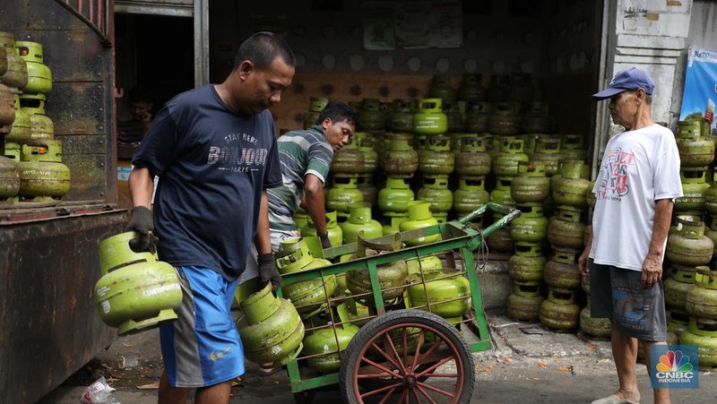 Pekerja menurunkan Liquefied Petroleum Gas (LPG) bersubsidi tabung 3 kilogram (kg) dari truk di pangkalan resmi LPG 3 kg Pertamina di Kawasan Jakarta, Selasa (2/1/2024). (CNBC Indonesia/Tri Susilo)