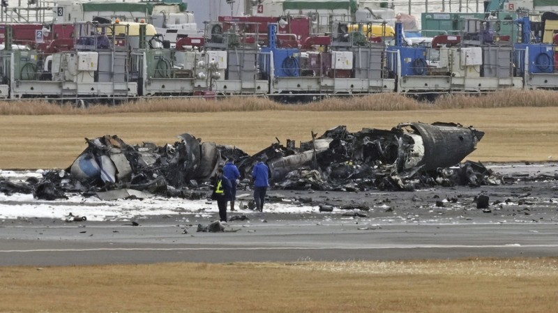 Japan Plane Fire The burn-out Japan Airlines plane is seen, at rear, at Haneda airport on Wednesday, Jan. 3, 2024, in Tokyo, Japan. The large passenger plane and a Japanese coast guard aircraft collided on the runway at Tokyo's Haneda Airport on Tuesday and burst into flames, killing several people aboard the coast guard plane, officials said. (Kyodo News via AP)