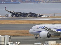 The burn-out Japan Airlines plane is seen, at rear, at Haneda airport on Wednesday, Jan. 3, 2024, in Tokyo, Japan. The large passenger plane and a Japanese coast guard aircraft collided on the runway at Tokyo's Haneda Airport on Tuesday and burst int