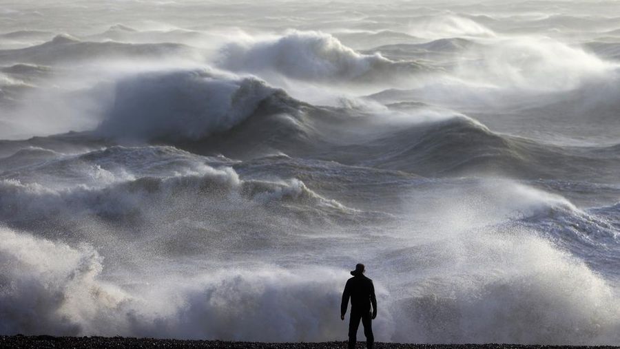 Seseorang melihat ke arah ombak yang menerjang pantai di Newhaven pada 2 Januari 2024, saat Badai Henk diperkirakan akan membawa angin kencang dan hujan lebat di sebagian besar wilayah selatan Inggris. (ADRIAN DENNIS/AFP via Getty Images)