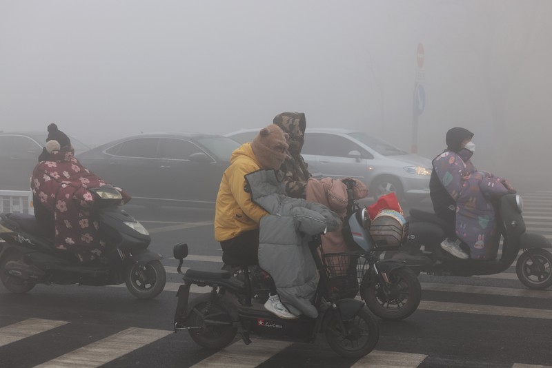 Warga berkendara saat kabut tebal dan udara yang tercemar di Jalan Wenhua Barat di Zaozhuang, Tiongkok, pada 3 Januari 2024.(Photo by Costfoto/NurPhoto via Getty Images)