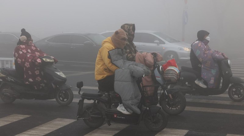Warga berkendara saat kabut tebal dan udara yang tercemar di Jalan Wenhua Barat di Zaozhuang, Tiongkok, pada 3 Januari 2024.(Photo by Costfoto/NurPhoto via Getty Images)