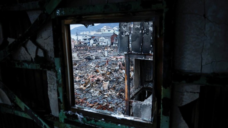 Seorang pria berjalan di sepanjang Jalan Asaichi-dori yang terbakar akibat gempa bumi, di Wajima, Jepang, 4 Januari 2024. (REUTERS/Kim Kyung-Hoon)