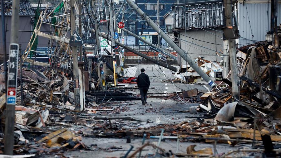 Seorang pria berjalan di sepanjang Jalan Asaichi-dori yang terbakar akibat gempa bumi, di Wajima, Jepang, 4 Januari 2024. (REUTERS/Kim Kyung-Hoon)
