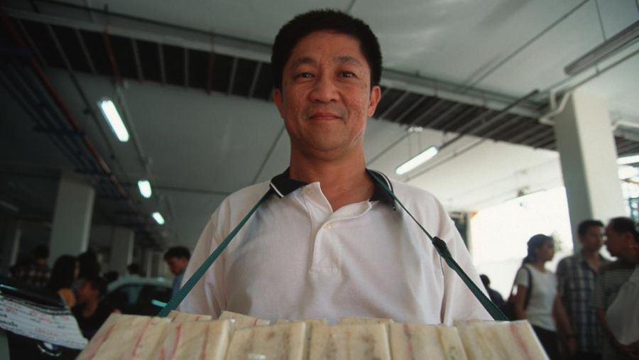 BANGKOK, THAILAND - 1997/12/10: Khun Sirivat (Siriwat) Voravetvuthikun has turned to selling sandwiches since the failure of a real estate venture. His logo depicts the Thai currency (baht) floating skywards. Since July, the Thai baht has lost more than 50% of its value against the dollar.. (Photo by Yvan Cohen/LightRocket via Getty Images)