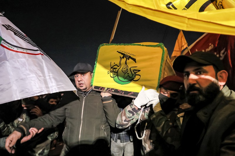 1900337400 Members of Iraq's Popular Mobilisation Forces (PMF) paramilitaries carry the bodies of two of their slain comrades during their funeral at the PMF headquarters in Baghdad on January 4, 2024. A US strike in Baghdad on January 4 killed a military commander of the PMF, an ex-paramilitary faction of the grouping said, with an Iraqi security official reporting two deaths in a drone attack. Harakat al-Nujaba, one of the PMF's factions, said in a statement that