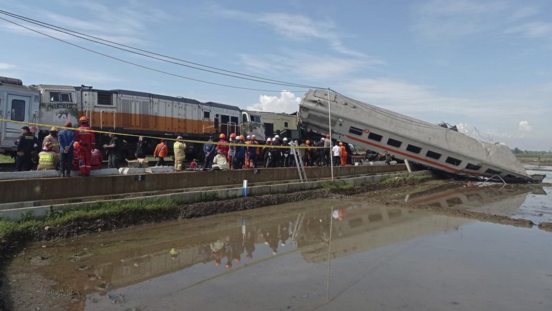 Rescuers inspect the wreckage of trains after a collision in Cicalengka, West Java, Indonesia, Friday, Jan. 5, 2024. The two trains collided on Indonesia's main island of Java on Friday, causing several carriages to buckle and overturn and killing a number of people, officials said. (AP Photo/Abdan Syakura)