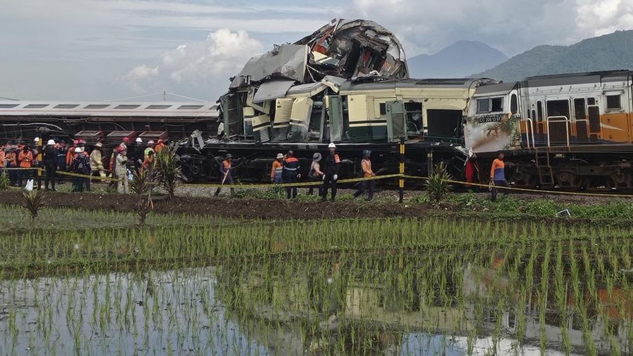 Tim penyelamat berjalan di dekat puing-puing kereta api setelah tabrakan di Cicalengka, Jawa Barat, Indonesia, Jumat, 5 Januari 2024. Kedua kereta itu bertabrakan di pulau utama Indonesia, Jawa, pada hari Jumat, menyebabkan beberapa gerbong tertekuk dan terbalik. (AP Photo/Abdan Syakura)