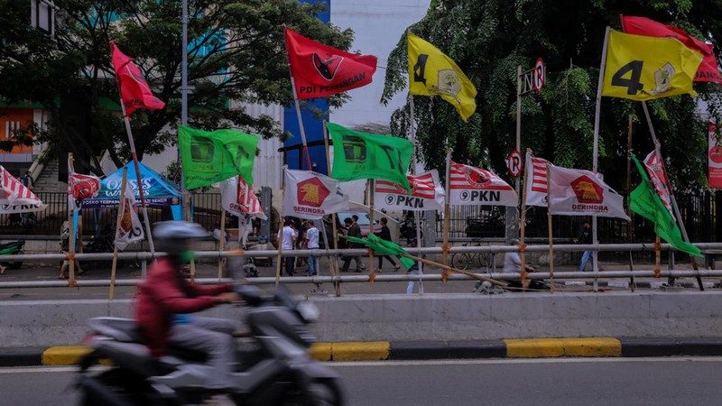 Kendaraan melintas di dekat bendera Partai Politik yang terpasang pada pembatas jalan di Jakarta, Senin (8/1/2023). (CNBC Indonesia/Faisal Rahman)