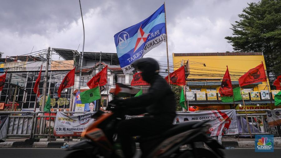 Kendaraan melintas di dekat bendera Partai Politik yang terpasang pada pembatas jalan di Jakarta, Senin (8/1/2023). (CNBC Indonesia/Faisal Rahman)