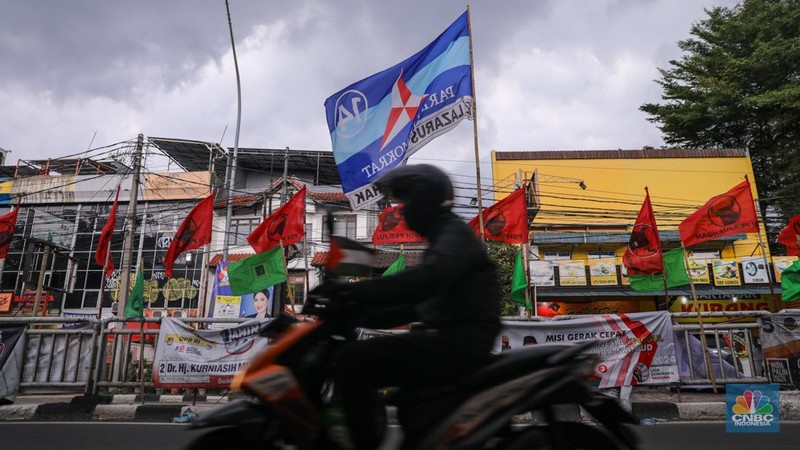 Kendaraan melintas di dekat bendera Partai Politik yang terpasang pada pembatas jalan di Jakarta, Senin (8/1/2023). (CNBC Indonesia/Faisal Rahman)