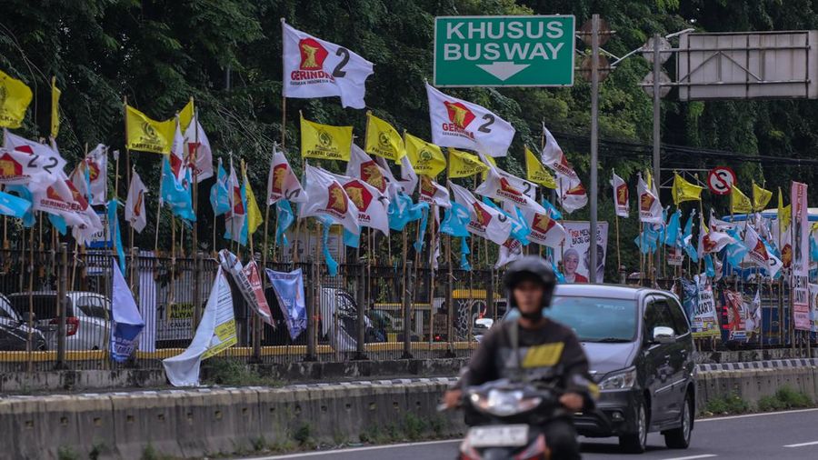 Kendaraan melintas di dekat bendera Partai Politik yang terpasang pada pembatas jalan di Jakarta, Senin (8/1/2023). (վ/Faisal Rahman)