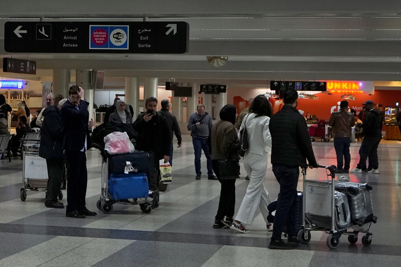 Wisatawan mendorong barang bawaan mereka di terminal keberangkatan Bandara Internasional Rafik Hariri di Beirut, Lebanon, Senin, 8 Januari 2024. Layar tampilan informasi pada hari Minggu di bandara internasional Beirut diretas oleh kelompok anti-Hizbullah domestik, saat bentrokan antara Kelompok militan Lebanon dan militer Israel terus menguat di sepanjang perbatasan. Informasi keberangkatan dan kedatangan pada hari Minggu digantikan oleh pesan yang menuduh kelompok Hizbullah menempatkan Lebanon dalam risiko perang habis-habisan dengan Israel. (AP Photo/Bilal Hussein)