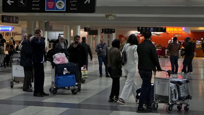 Wisatawan mendorong barang bawaan mereka di terminal keberangkatan Bandara Internasional Rafik Hariri di Beirut, Lebanon, Senin, 8 Januari 2024. Layar tampilan informasi pada hari Minggu di bandara internasional Beirut diretas oleh kelompok anti-Hizbullah domestik, saat bentrokan antara Kelompok militan Lebanon dan militer Israel terus menguat di sepanjang perbatasan. Informasi keberangkatan dan kedatangan pada hari Minggu digantikan oleh pesan yang menuduh kelompok Hizbullah menempatkan Lebanon dalam risiko perang habis-habisan dengan Israel. (AP Photo/Bilal Hussein)